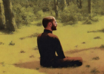 Ein Mann sitzt im Gras und meditiert