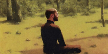 Ein Mann sitzt im Gras und meditiert